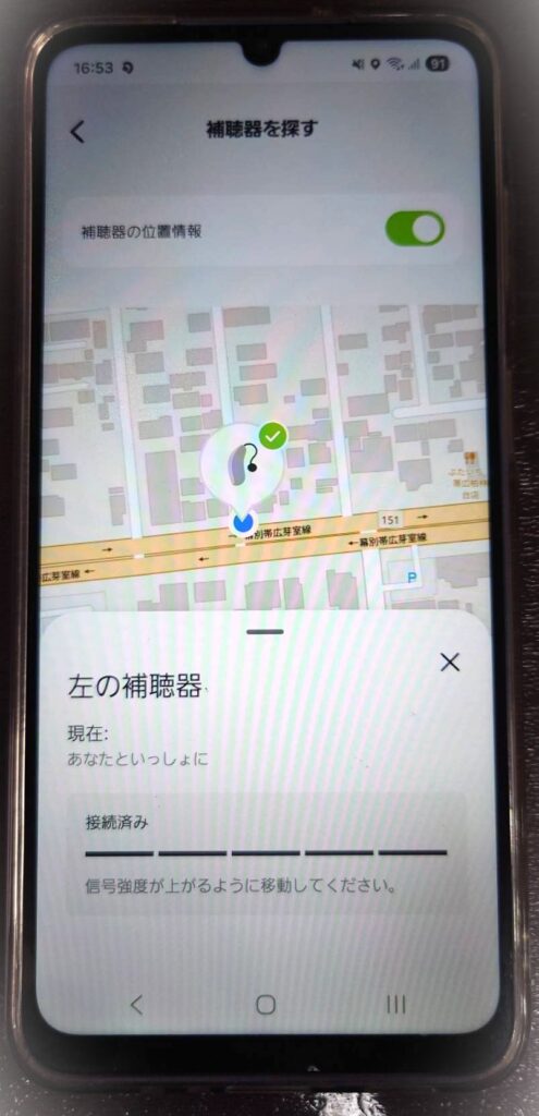 スマートフォンの補聴器アプリで補聴器の位置を地図上に表示している画面イメージ。左の補聴器が接続中で現在地付近にあることを示し、補聴器を探す機能の使用例を表現した写真。補聴器を紛失した際や見失った場合に役立つ機能で、Bluetooth接続により位置情報や接続状況を確認できることを解説するブログ内容に対応。補聴器アプリ、補聴器 紛失 防止、補聴器 探す機能、スマホ連携補聴器などの、わかば補聴器センター帯広店・函館本店が提供する最新補聴器の便利機能を紹介する画像説明。帯広・函館・十勝・道東・道南エリアで補聴器を探している方や、スマホ連携機能に興味がある方に向けたイメージ。